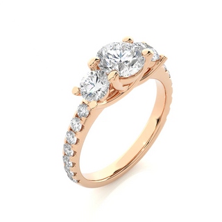 Angled view of 2.50 Carat Round Moissanite Trellis Prong Three Stone Engagement Ring in Rose Gold, showcasing the band and setting.​