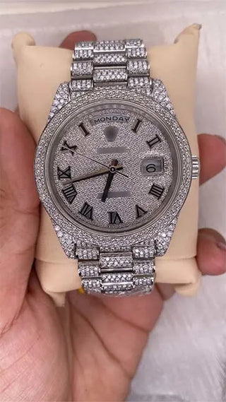 Front view of a replica moissanite watch with Roman numerals, day and date display, and full pavé stone dial and strap.