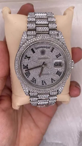 Front view of a replica moissanite watch with Roman numerals, day and date display, and full pavé stone dial and strap.