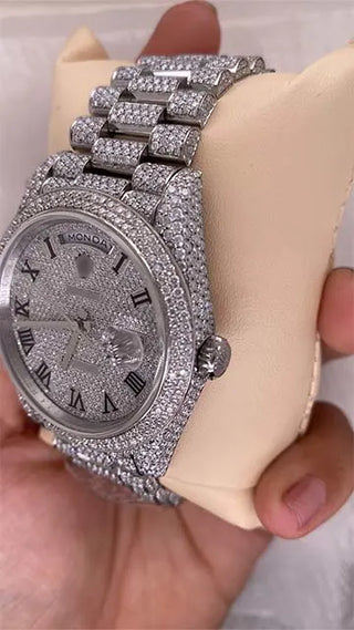 Side view of a replica moissanite watch showing the stone-studded case, crown, and part of the dial with Roman numerals.