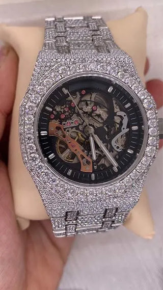 Affordable skeleton-style watch with clear case showing gears, covered in shiny moissanite stones on dial and band.
