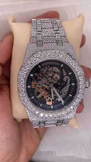 Affordable skeleton-style watch with clear case showing gears, covered in shiny moissanite stones on dial and band.