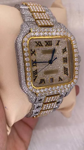 Side view of a moissanite watch for men showing the iced bezel, crown, and two-tone metal band, held in hand.