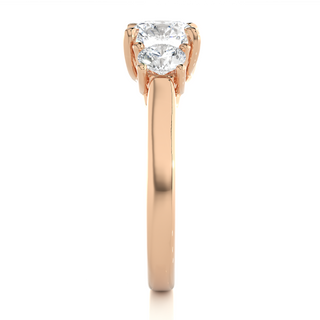 Side profile of 1.50 Ct Round Moissanite Three Stone Engagement Ring In Rose Gold, highlighting the brilliant center moissanite stone., highlighting the prong setting.