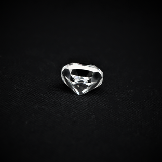 Back view of a cushion-cut moissanite resting on a black textured surface, highlighting its pavilion and faceted structure.