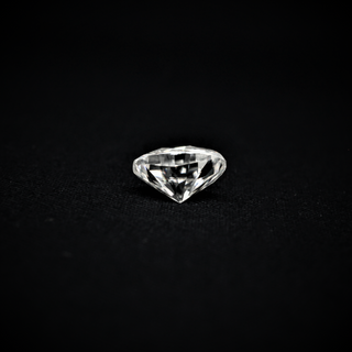 Back view of a loose round brilliant-cut moissanite gemstone displaying its faceted pavilion against a black background.